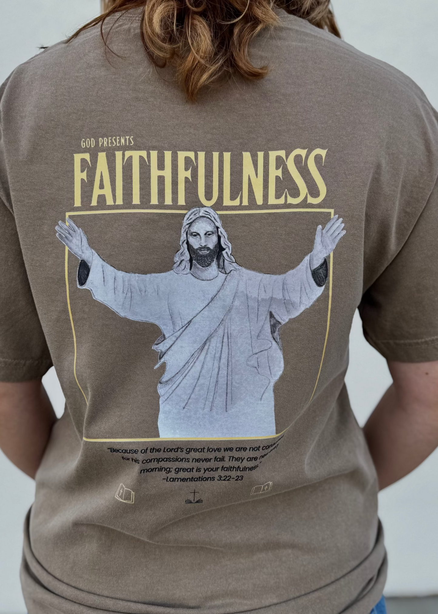 Person wearing a brown t-shirt with a graphic of Jesus and the word 'Faithfulness' on the back.